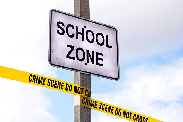 A "SCHOOL ZONE" sign with cordon tape that reads "CRIME SCENE DO NOT CROSS".