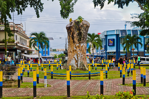 Castries, Saint Lucia - November 26, 2011: people crowding the Castries downtown, full of shops, street vendors and traffic. The poles of the square have been painted in black, yellow and blue, the colors of the Saint Lucia flag.