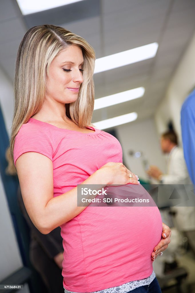 Linda mulher grávida segurando a barriga no corredor do hospital - Foto de stock de Abdômen Humano royalty-free