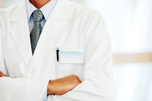 Close up of a doctor with a blank name tag standing with arms crossed.   
