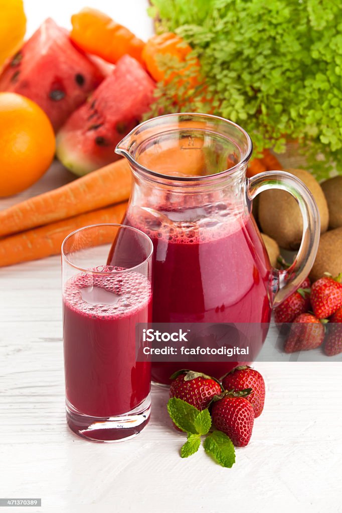 Strawberry Smoothie Glass and Jug of Strawberry Smoothie on White Garden Table. Blended Drink Stock Photo