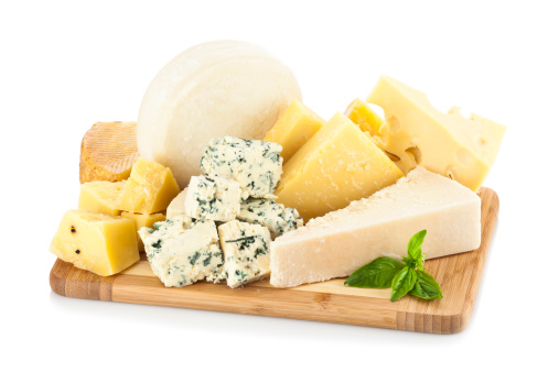A wooden cheese board filled with a various types of cheese shot on white backdrop. Parmesan cheese, emmental and roquefort, are some of the cheeses includes in the image.  Soft shadow of the wood board on background.  The predominant color is white and yellow. DSRL studio shot with Canon EOS 5D Mk II  