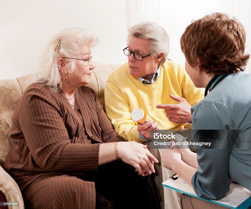 Doctor Senior pareja discutiendo con el medicamento - Foto de stock de 30-39 años libre de derechos