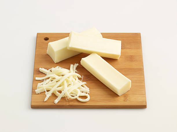 Cheese blocks and shaved cheese on chopping board String Cheese On Chopping Board shredded mozzarella stock pictures, royalty-free photos & images