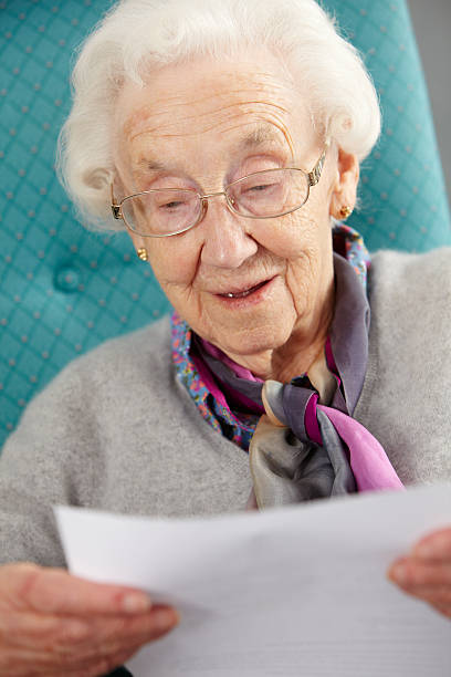 femme âgée se détendre dans une chaise de lecture de lettres - senior adult independence lifestyles home interior photos et images de collection