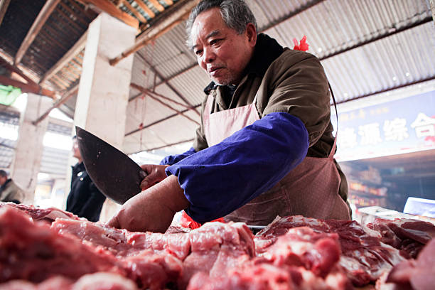 Yangshuo, China - March 15, 2012: Chinese butcher working and selling meat in the food market of Yang Shuo.