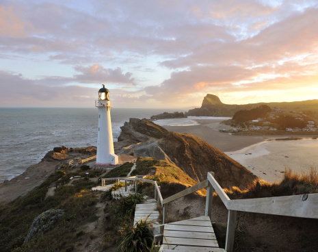 Dramatic golden sunset beams illuminate the Castle Point Lighthouse - it is near the village of Castlepoint in the Wellington Region of the North Island of New Zealand.