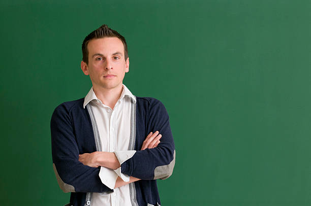 istock serious teacher with arms crossed at blackboard 471376889