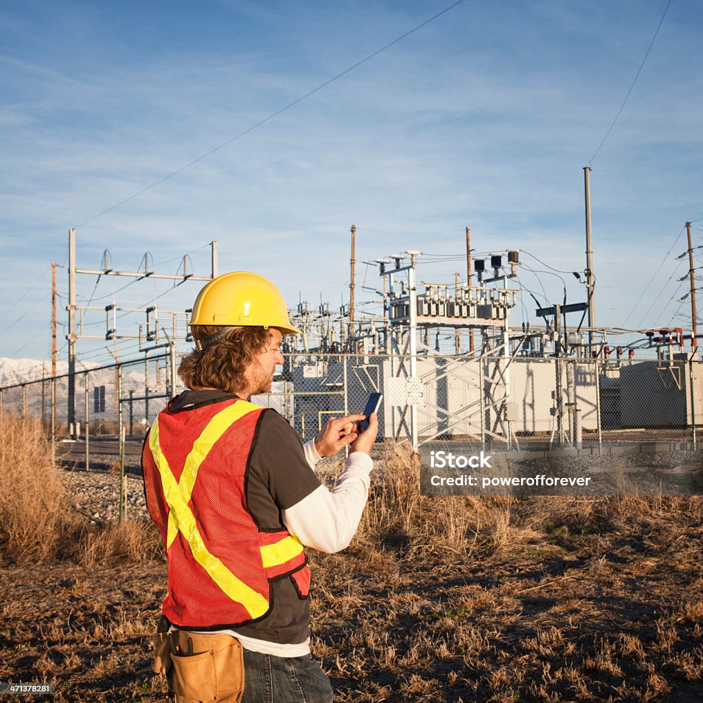 Ligne à haute tension technicien en utilisant le téléphone intelligent - Photo de Production d'énergie libre de droits