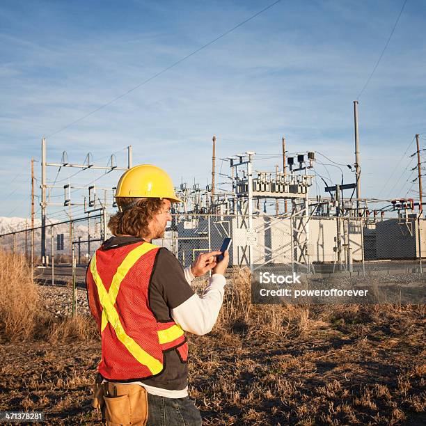 Photo libre de droit de Ligne À Haute Tension Technicien En Utilisant Le Téléphone Intelligent banque d'images et plus d'images libres de droit de Production d'énergie