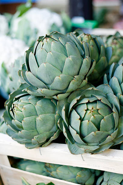 Fresh artichokes in a wood crate for sale at an outdoor farmer's market in Paris, France.