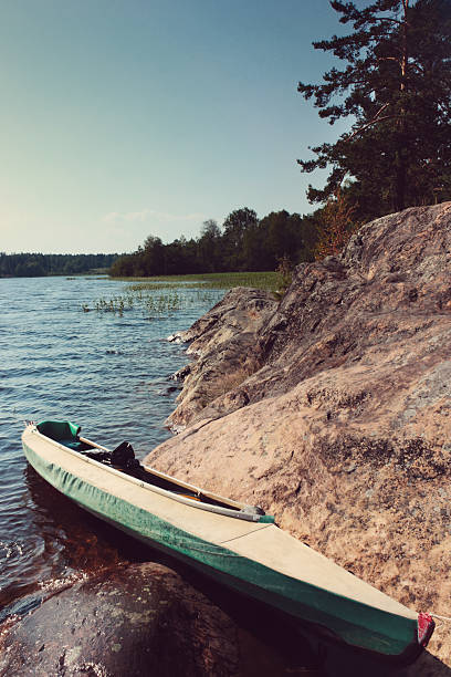 Canoe at camp on the shore of the beautiful lake at summer day under blue sky with light clouds. Toning effect done with a vintage retro Instagram style filter