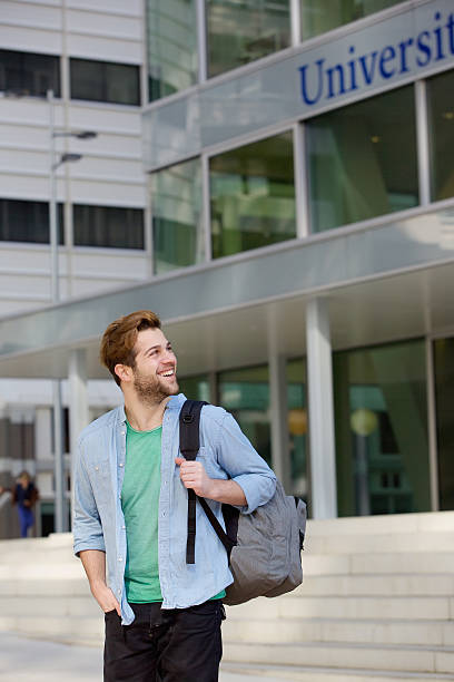 istock Happy male student standing on campus with bag 471379228