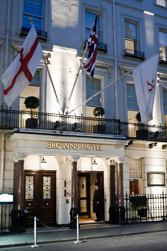 London, England - February 7, 2011: The Browns Hotel at dusk. The doorman standing and waiting for guests. The Browns is a 5 star hotel located in Mayfair.