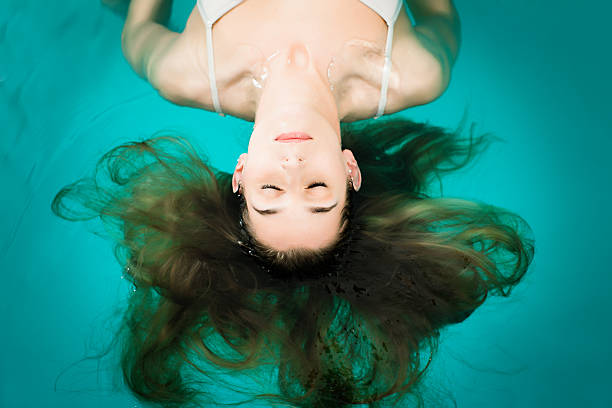 wellness-giovane donna galleggianti in piscina o nella spa - galleggiare sullacqua foto e immagini stock