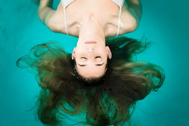 Wellness - young woman floating in Spa or swimming pool, she is very relaxed