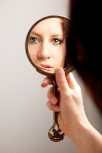A closeup mirror reflection of a woman's face, selective focus