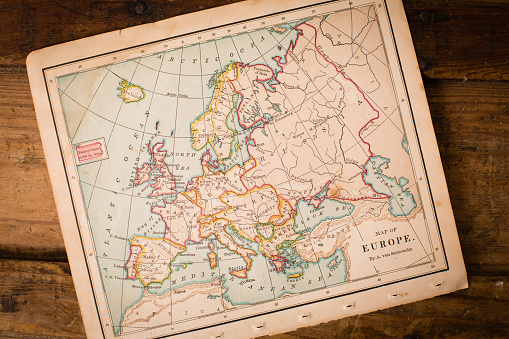 Color image of an old color map of Europe, sitting at an angle, on antique wood trunk.