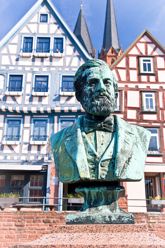 Bronze bust in the historic district downtown Gelnhausen, Germany, the birthplace of Philip Reis. Johann Philipp Reis (January 7, 1834 in Gelnhausen, † January 14, 1874 in Friedrichsdorf) was a German physicist and inventor. Inventor of a device for transmitting sound over electrical lines. In 1861 he gave his apparatus the name Telehone. In the background, In the background, half-timbered houses and the Church of St. Mary houses and the Church Marienkirche.