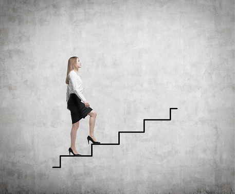 Young business woman is going up to the stairs. A concept of successful business project