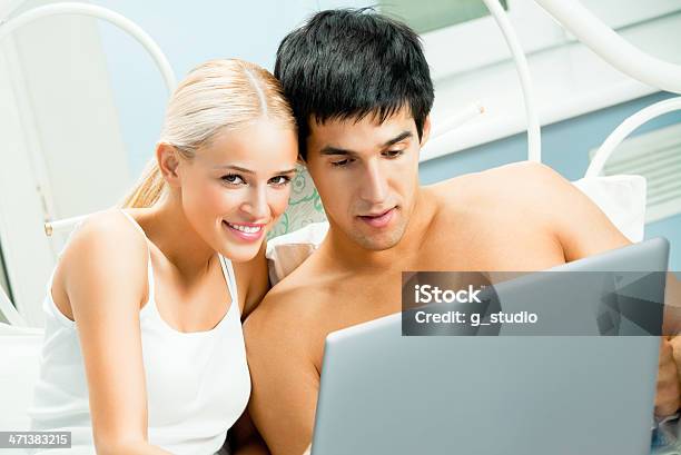 Pareja Joven De Trabajo Con Computadora Portátil Foto de stock y más banco de imágenes de Acostado - Acostado, Adulto, Adulto joven