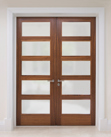 a pair of tall walnut doors set in a white frame, from a very expensive new home. These door s have been beautifully crafted, as have the frames - see the skirting board and frame near the bottom corners. The floor is Italian marble. The glass panes have frosted glass.