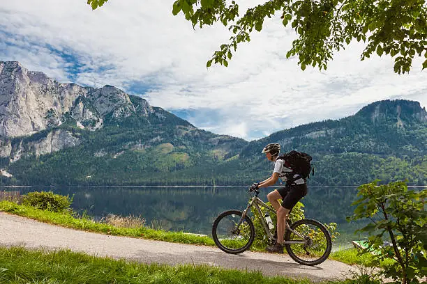 A young, female mountainbiker on her ride lakeside the scenic Lake Altaussee in the Ausseerland Region, Styria, Austria.