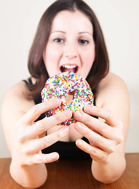istock Young woman eating doughnut 471387375