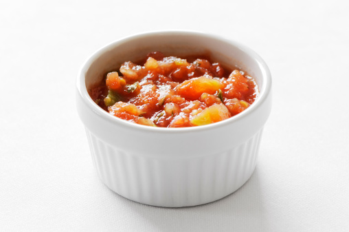 Bowl of chunky tomato salsa on a white background.