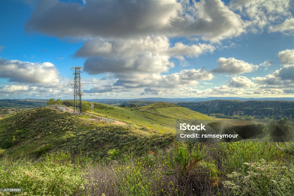 Cell Tower in the wilderness A cellular communication tower, repeater station sitting high atop a hill in a wilderness area with houses in the far distance. Beauty In Nature Stock Photo