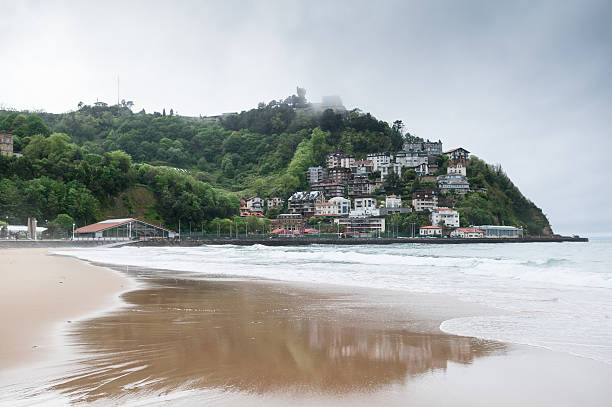 View of a beach in San Sebastian - Donostia,  Capital city of Gipuzkoa in the Basque Autonomous Community in Spain. The touristic costal city lies on the coast of the Bay of Biscay, 20 km from the French border. Panoramic. Shot during a cloudy and rainy day in spring season