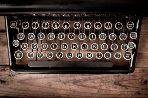 Close up, color image of the keys of a vintage,  black, manual typewriter on wood trunk.