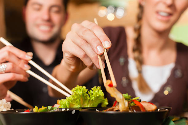 istock Young people using chop sticks on food in a Thai restaurant 471396703