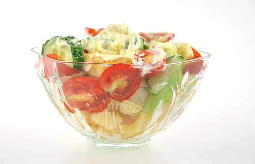 Colorful fruit salad wit Kewpie in glass bowl on white background.