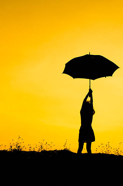 istock Umbrella girl with sunset silhouette 471397684