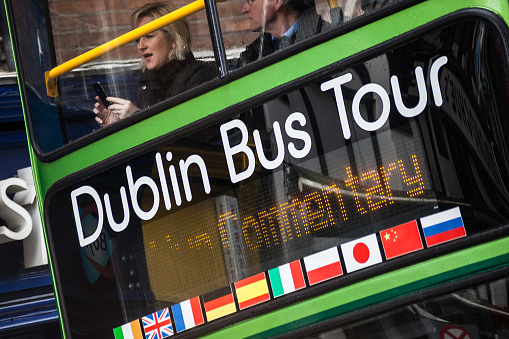 Dublin, Ireland - April 27, 2012: a woman takes a picture with a mobile phone from the deck of a Dublin Bus Tour in the city center of Dublin.