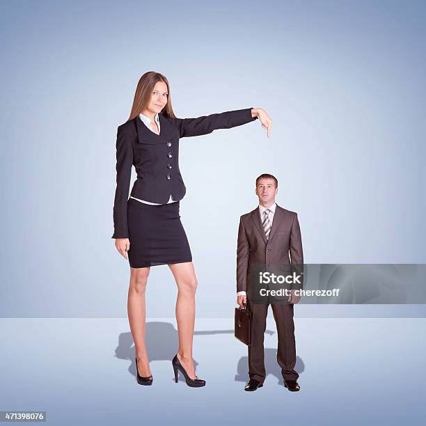 Sonriente Mujer De Negocios Joven Apuntando A Pequeñas Ejecutivo Foto de stock y más banco de imágenes de Persona alta