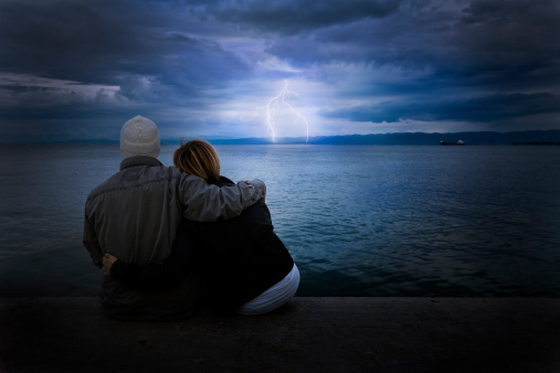 Couple looking at thunderstorm on the beach