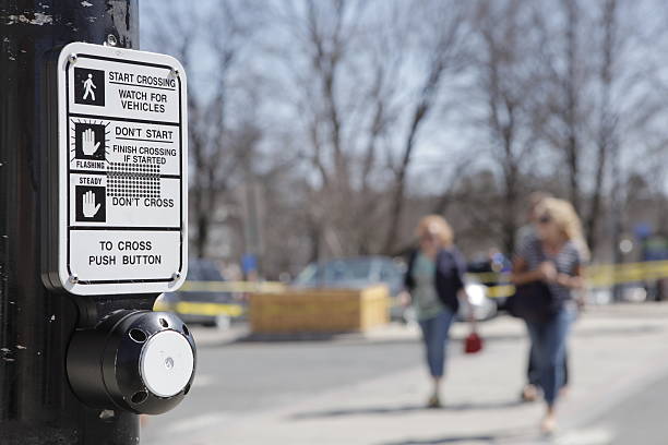 Crosswalk Close up, rack focus of a crosswalk sign and button. A red, blurred car drives by. pedestrian stock pictures, royalty-free photos & images