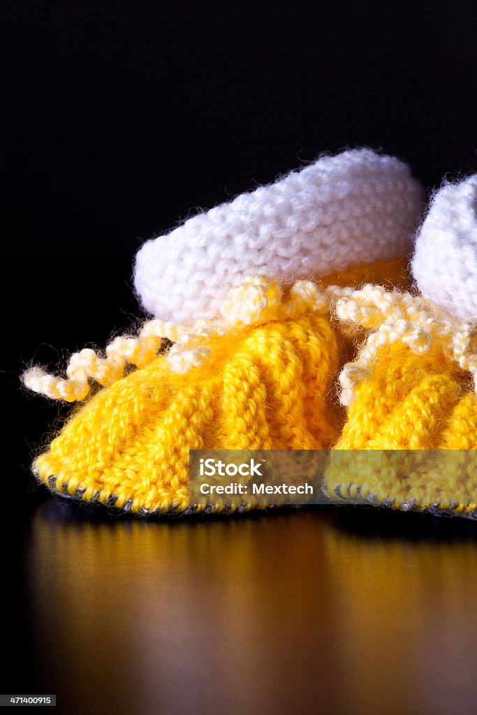 Knitted handmade baby's bootees Baby wool socks isolated on black background. Art And Craft Stock Photo