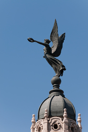 Bronze angel statue holding a wreath in her left hand at the end of her outstretched arm on the top of the Gran Teatro de La Habana, one of the world's largest opera houses completed in 1915 designed by Belgian architect Paul Belau.