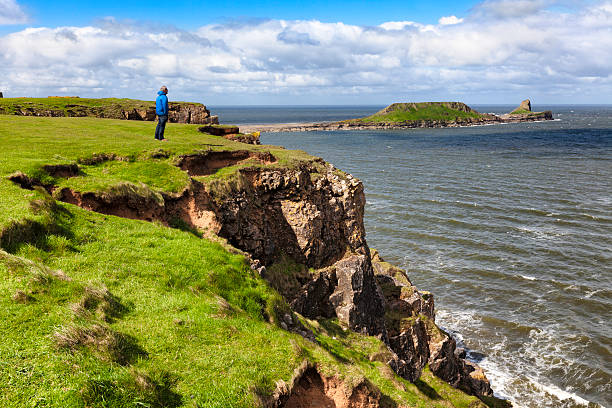 Man enjoying view of Worm's Head, Gower Peninsula, South Wales Man looking at Worm's Head from the Gower near Rhossilli. gower peninsular stock pictures, royalty-free photos & images