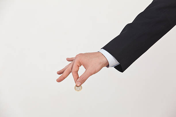 A senior man's hand holding a two Euro coin.