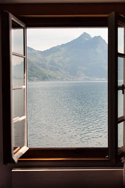 An open wood window with a lake and mountains view