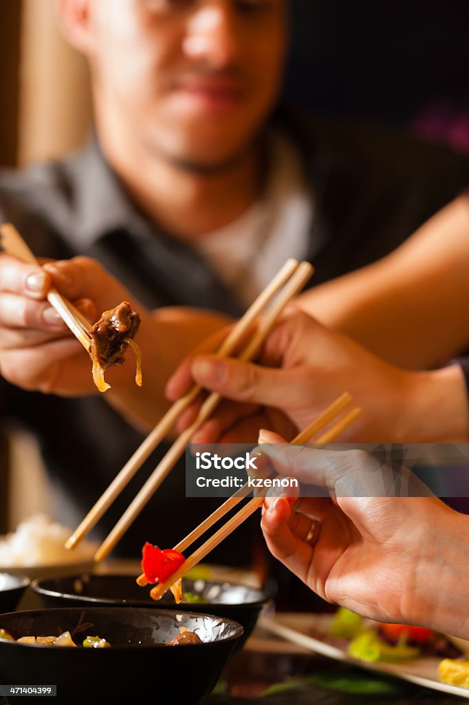 Young people eating in Thai restaurant Young people eating in a Thai restaurant, they eating with chopsticks Adult Stock Photo