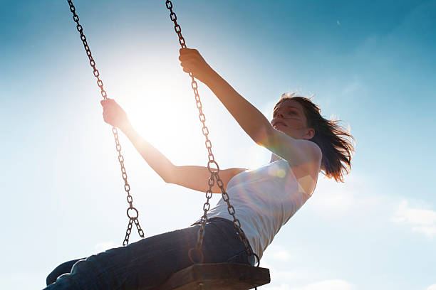 istock Girl Swinging Against Sun and Blue Sky 471406161