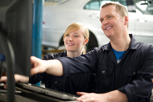 pomagając w garażu - trainee auto repair shop computer manual worker zdjęcia i obrazy z banku zdjęć