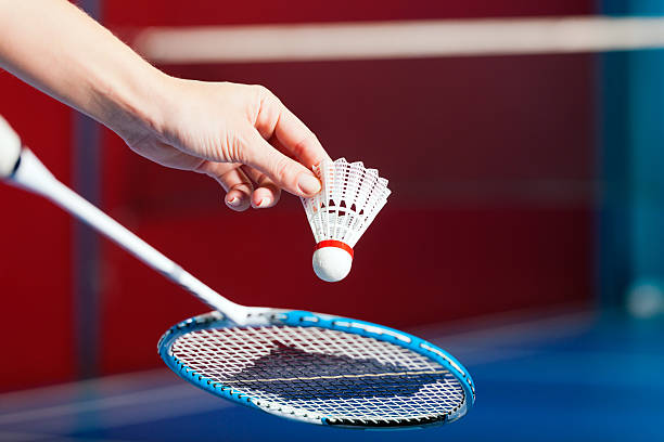 Badminton sport in gym - hand with shuttlecock Woman playing Badminton and doing sport in gym, only serve to be seen badminton racquet stock pictures, royalty-free photos & images