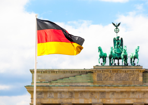 German flag in front of Brandenburg Gate in Berlin.