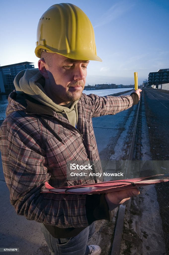 man with helmet and folder three quarter view of middle aged man with worker helmet and red folder. spreaded left arm with yardstick in the dusk 30-39 Years Stock Photo